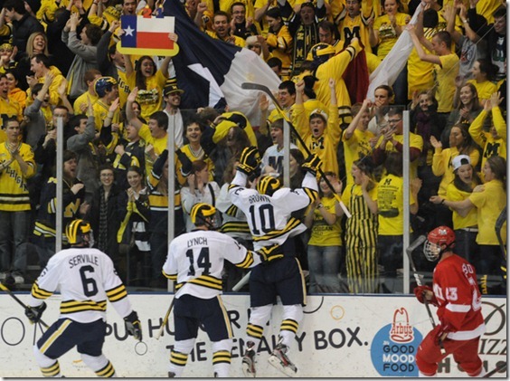 Michigan junior Chris Brown jumps up on the glass to cheering fans after scoring the first goal of the game, on the day of his birthday. Fans waved signs and Texas flags to celebrate his birthday. Angela J. Cesere | AnnArbor.com
