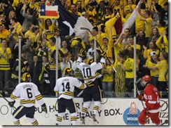 Michigan junior Chris Brown jumps up on the glass to cheering fans after scoring the first goal of the game, on the day of his birthday. Fans waved signs and Texas flags to celebrate his birthday. Angela J. Cesere | AnnArbor.com<br />
